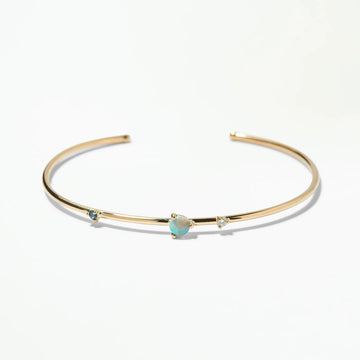 Gold bracelet with a sapphire, opal and diamonds on a white background