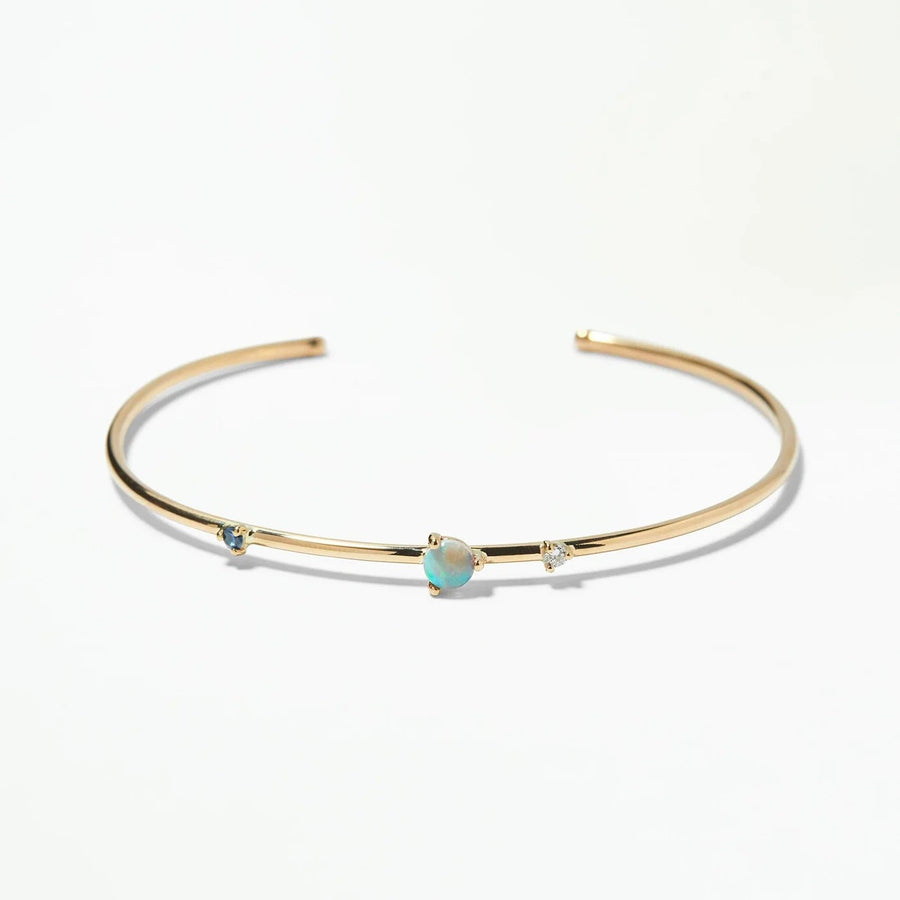 Gold bracelet with a sapphire, opal and diamonds on a white background