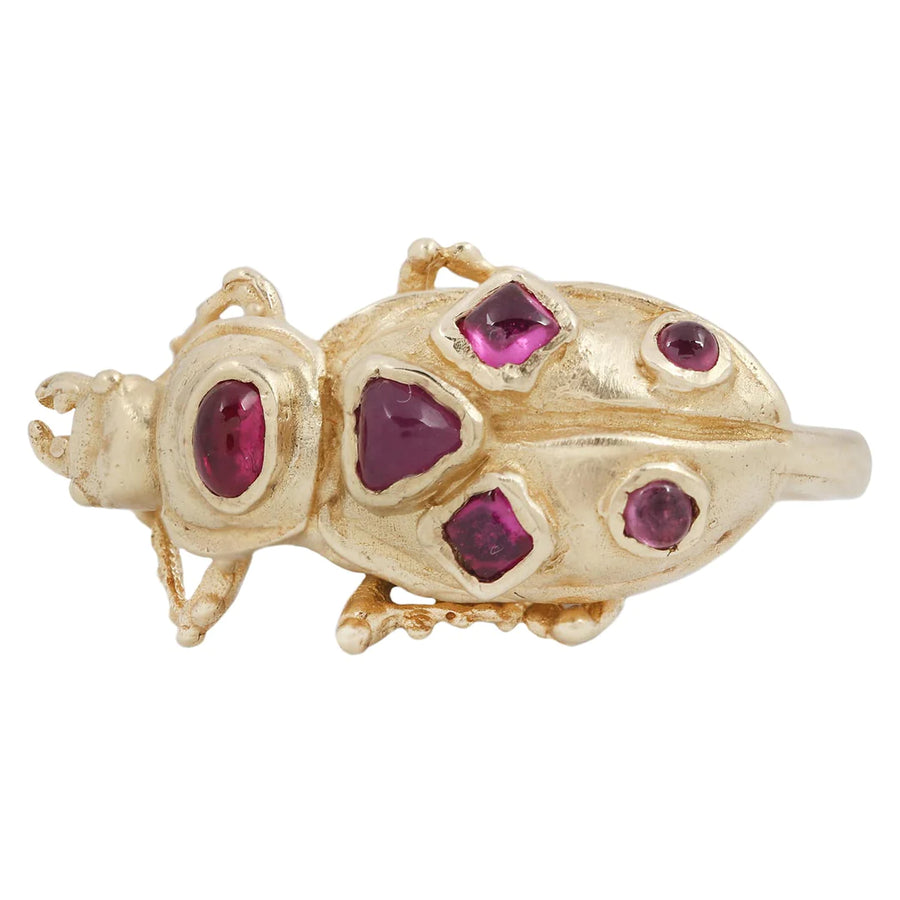 Piacate Beetle is featured on a ring in recycled 14k yellow gold with various shaped ruby cabochons scattered on its shell.