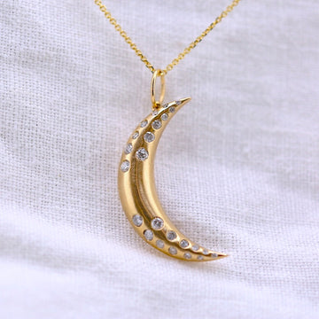 14k matte yellow gold crescent moon with flush set white diamonds scattered along the moon, on a 18