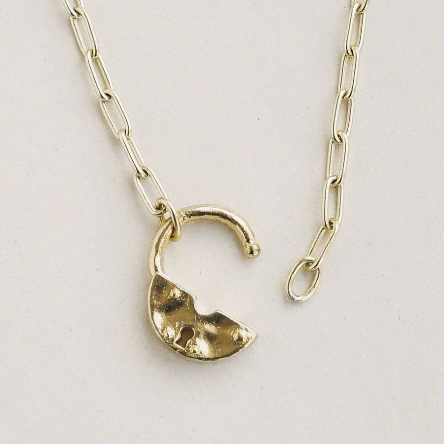Gold necklace with a unique pendant on a light gray background