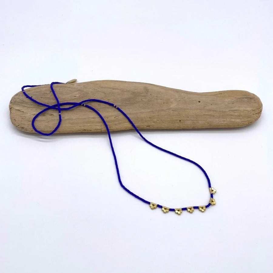 Blue necklace with gold beads on a wooden block against a white background