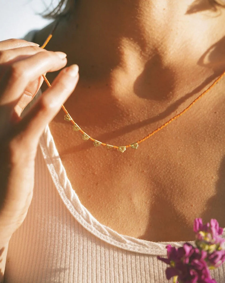 Close-up of a person wearing a delicate gold necklace with a blurred background