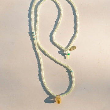 Necklace with green and gold pendants on a light background