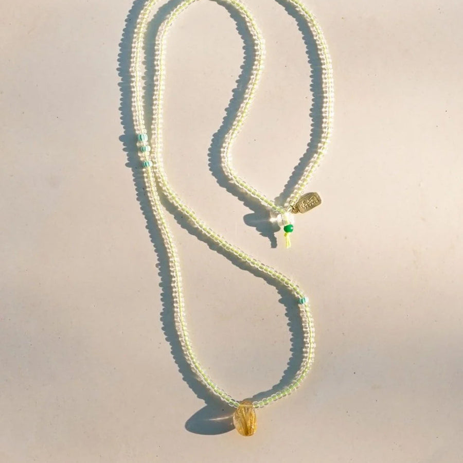Necklace with green and gold pendants on a light background