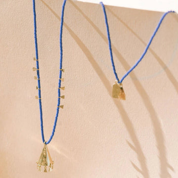 Gold necklace with blue beads on a beige background