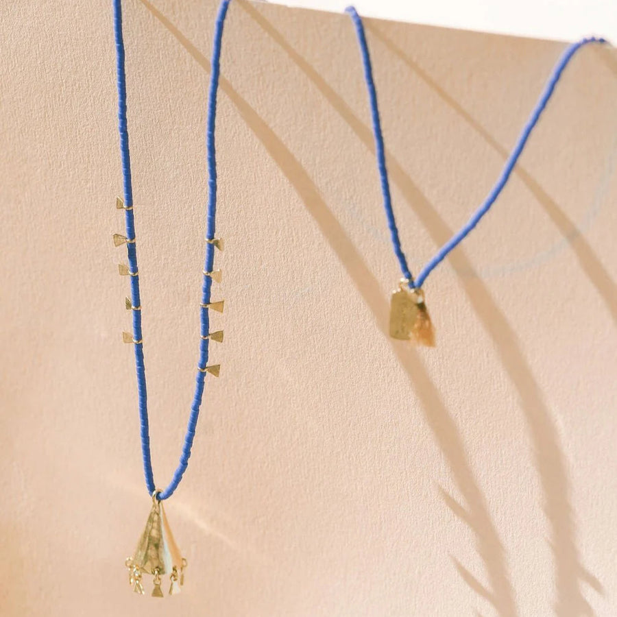 Gold necklace with blue beads on a beige background