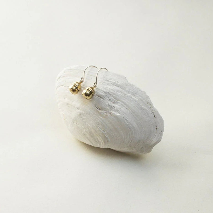 Gold earrings on a white stone with a plain background