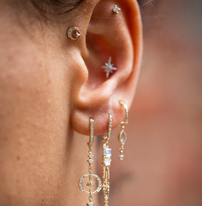 14K light yellow gold moon crescents with three pave set white diamonds, and a solid gold star in the center of each crescent on models ear-Marisa Mason