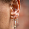 2 of 2: 14K light yellow gold moon crescents with three pave set white diamonds, and a solid gold star in the center of each crescent on models ear-Marisa Mason