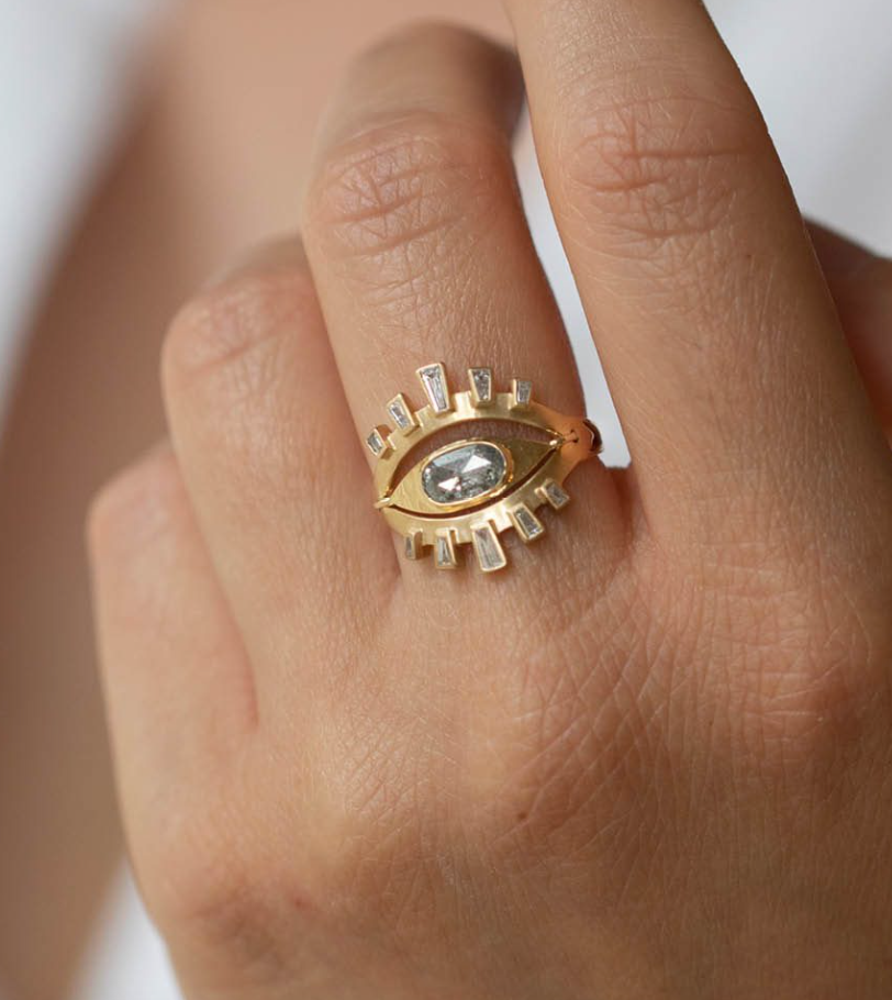14k yellow gold eye ring with one rose cut gray diamond, and ten gray baguette diamonds set in halos above and below it