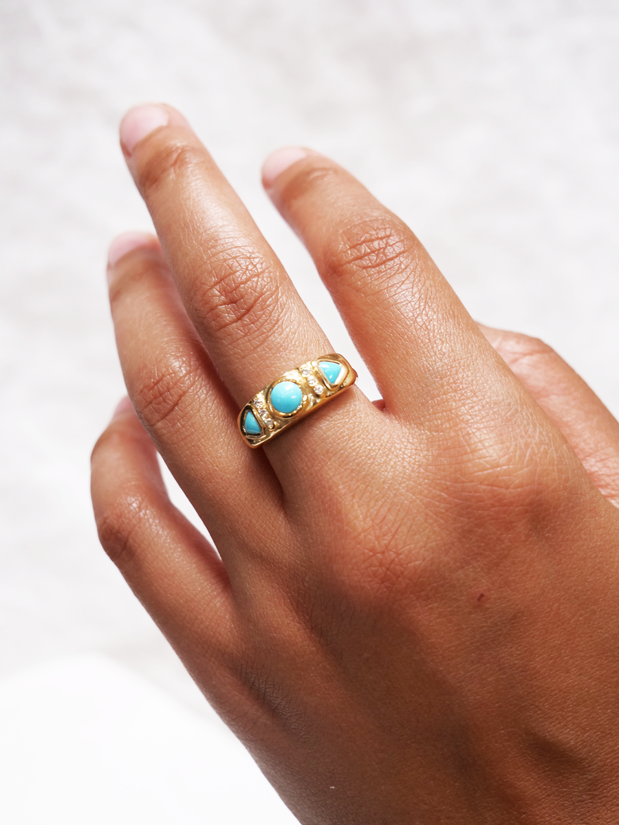 High polish 18k gold, set with a sleeping beauty turquoise round cabochon in the center, with three recycled melee diamonds in a row on either side, and two triangular turquoise cabochons after that shown on model-Marisa Mason